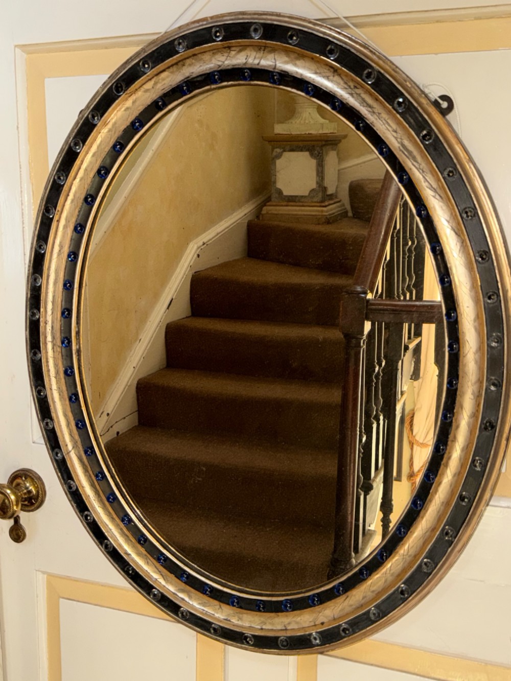 A nineteenth-century Irish oval wall mirror featuring an ebonised frame inset with clear facetted glass jewels, an inner silver-gilt band, and cobalt blue glass cabochons. View IX