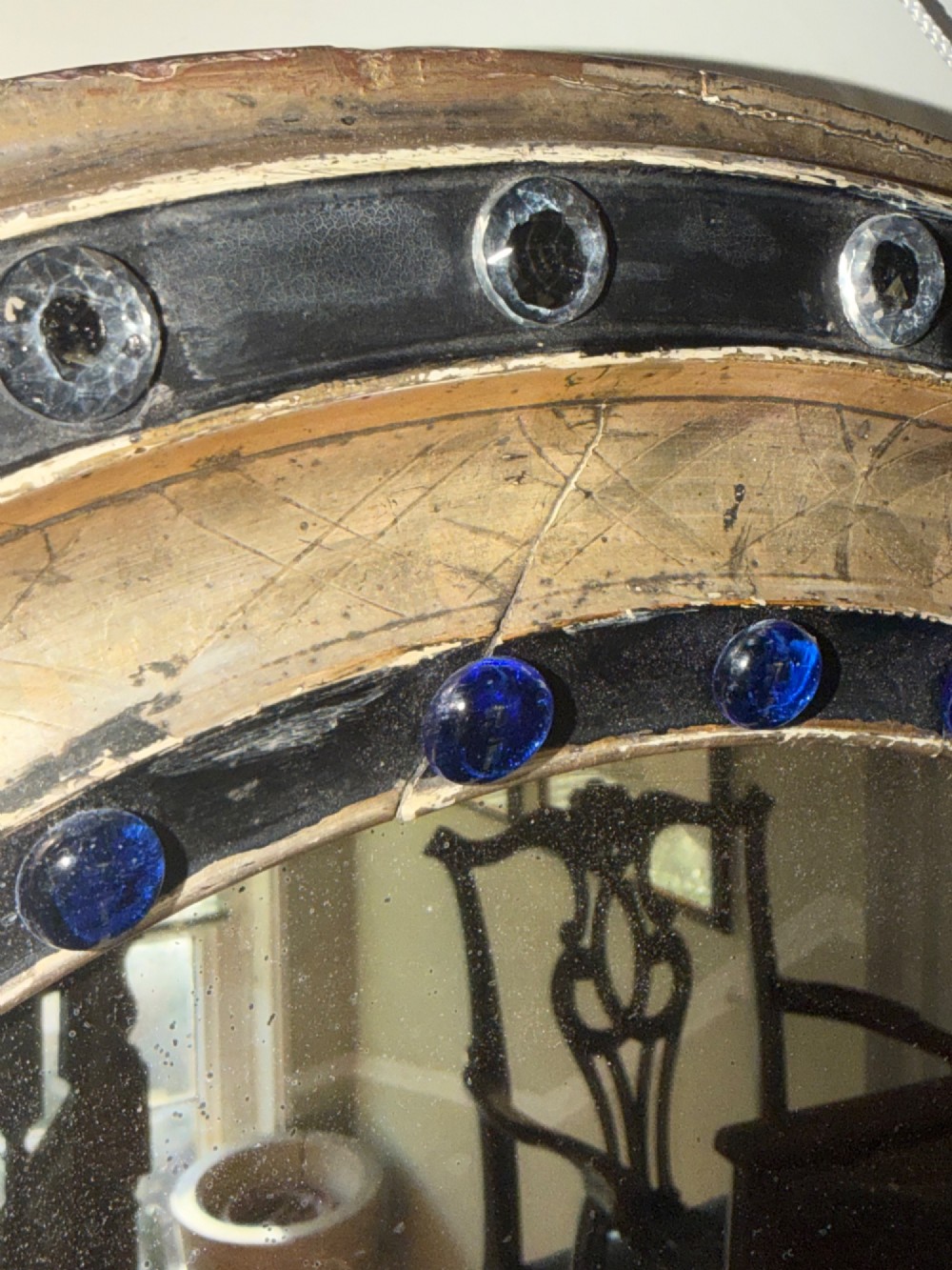 A nineteenth-century Irish oval wall mirror featuring an ebonised frame inset with clear facetted glass jewels, an inner silver-gilt band, and cobalt blue glass cabochons. View XI