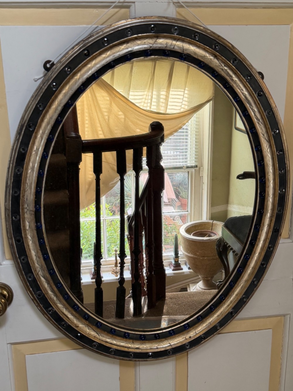 A nineteenth-century Irish oval wall mirror featuring an ebonised frame inset with clear facetted glass jewels, an inner silver-gilt band, and cobalt blue glass cabochons. View XIII