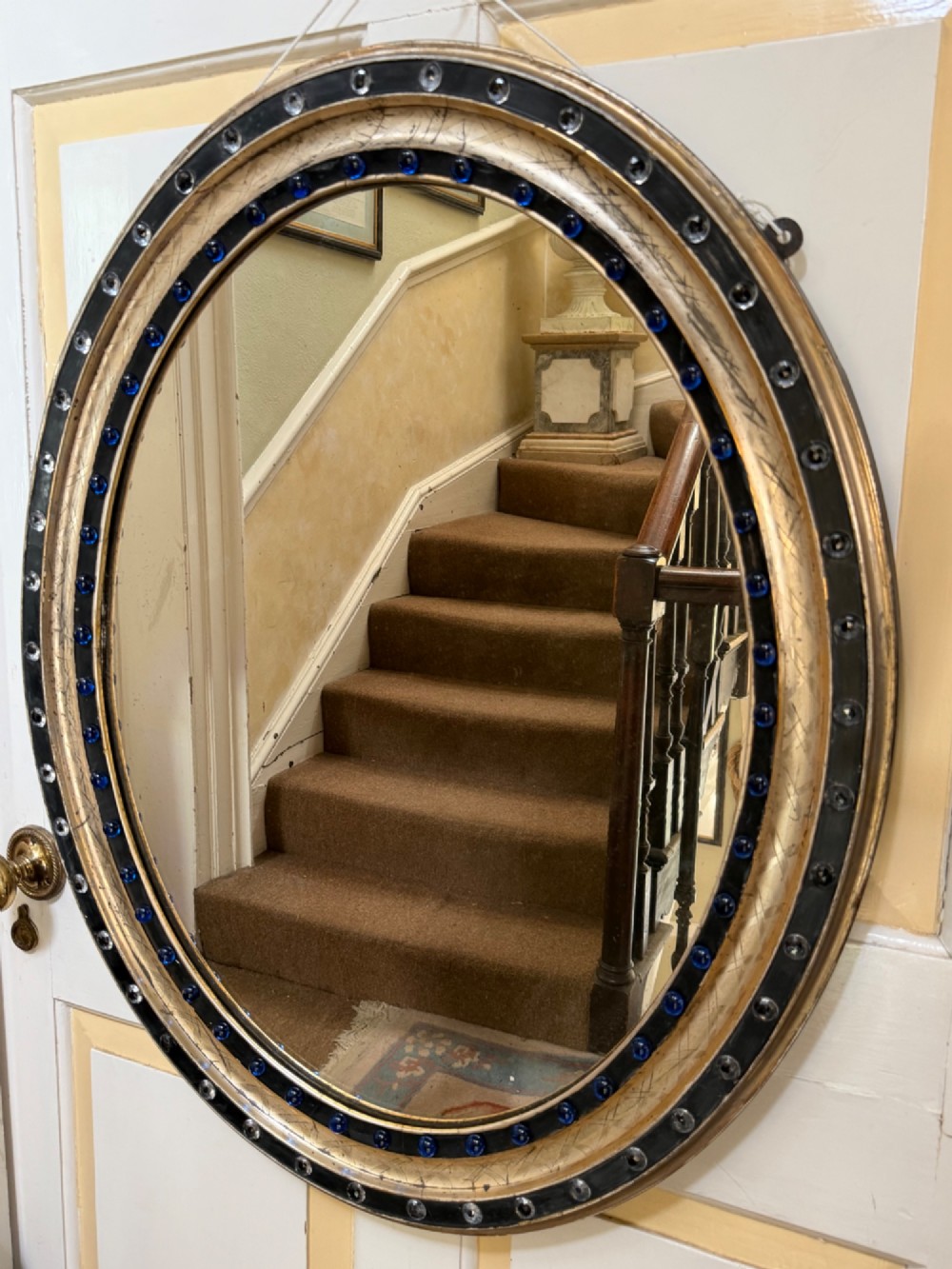 A nineteenth-century Irish oval wall mirror featuring an ebonised frame inset with clear facetted glass jewels, an inner silver-gilt band, and cobalt blue glass cabochons. View XIV