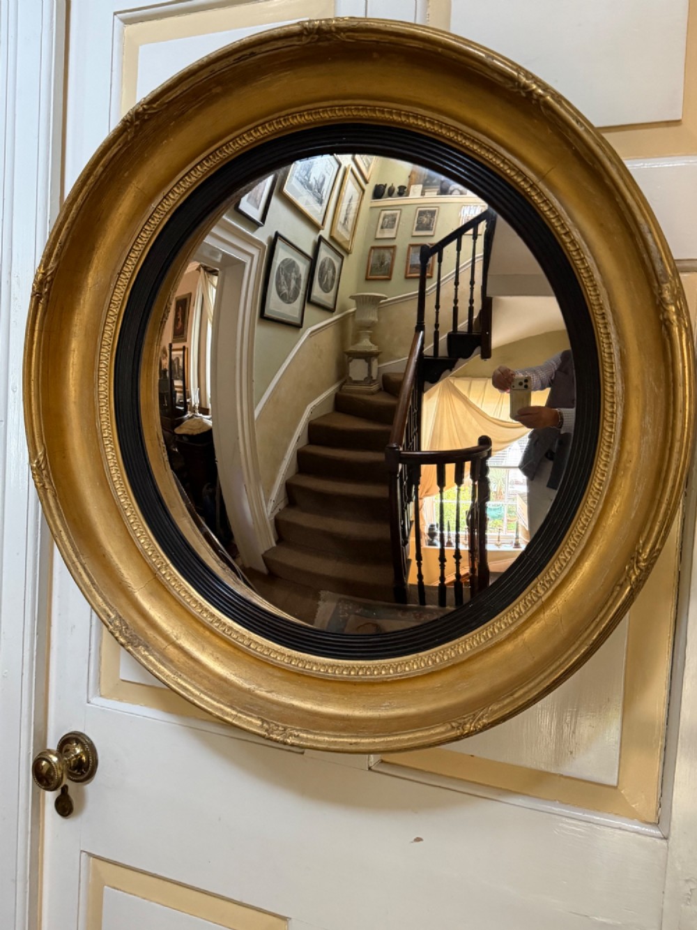 A circular early 19th-century Regency convex mirror featuring a gilded carved frame with an ebonised inner reeded slip. View II