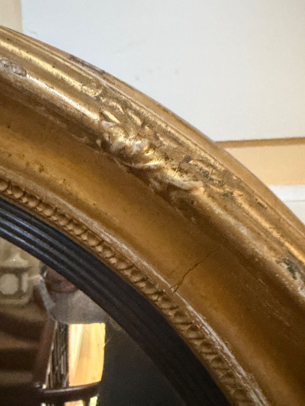 A circular early 19th-century Regency convex mirror featuring a gilded carved frame with an ebonised inner reeded slip. View III