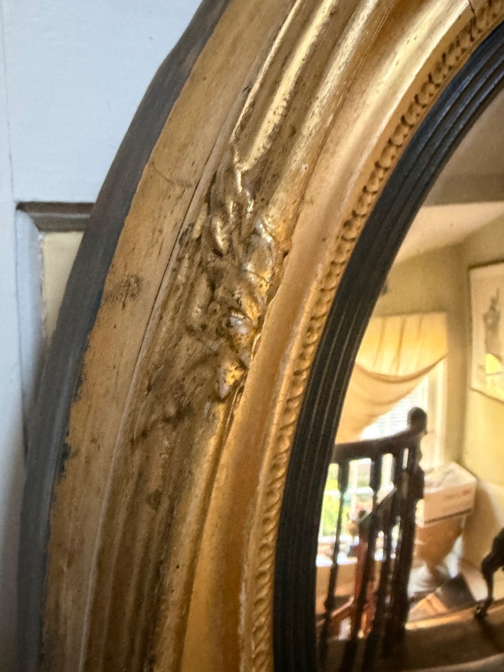 A circular early 19th-century Regency convex mirror featuring a gilded carved frame with an ebonised inner reeded slip. View VI