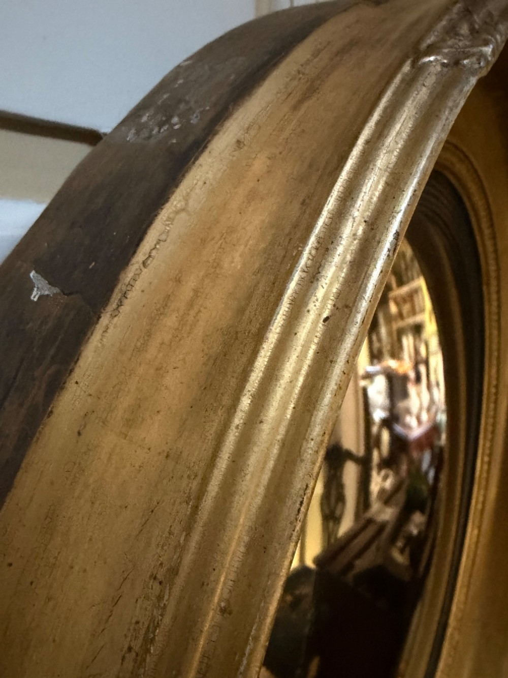 A circular early 19th-century Regency convex mirror featuring a gilded carved frame with an ebonised inner reeded slip. View VIII