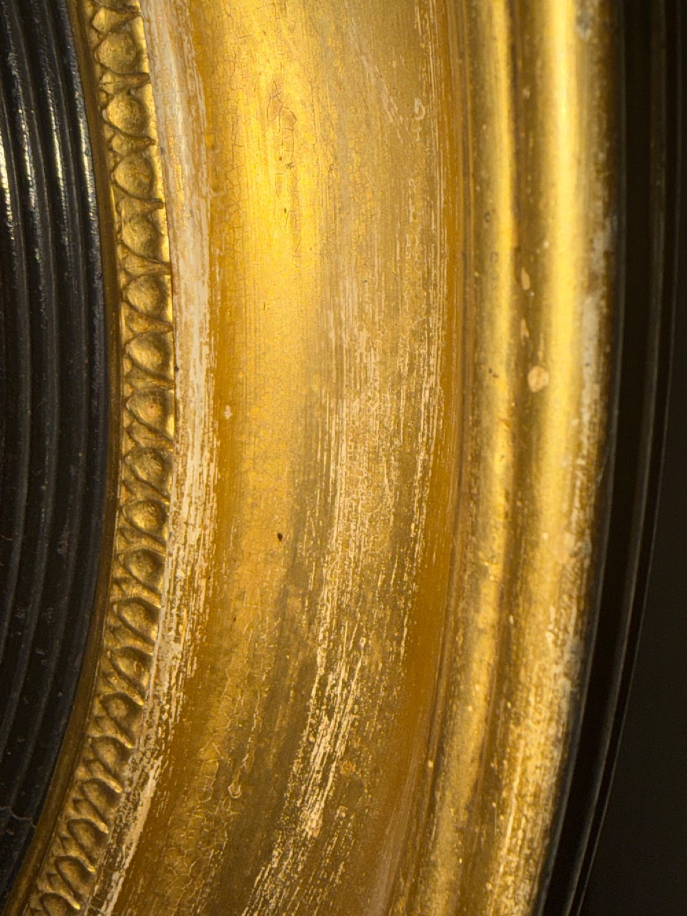 A circular early 19th-century Regency convex mirror featuring a gilded carved frame with an ebonised inner reeded slip. View XI