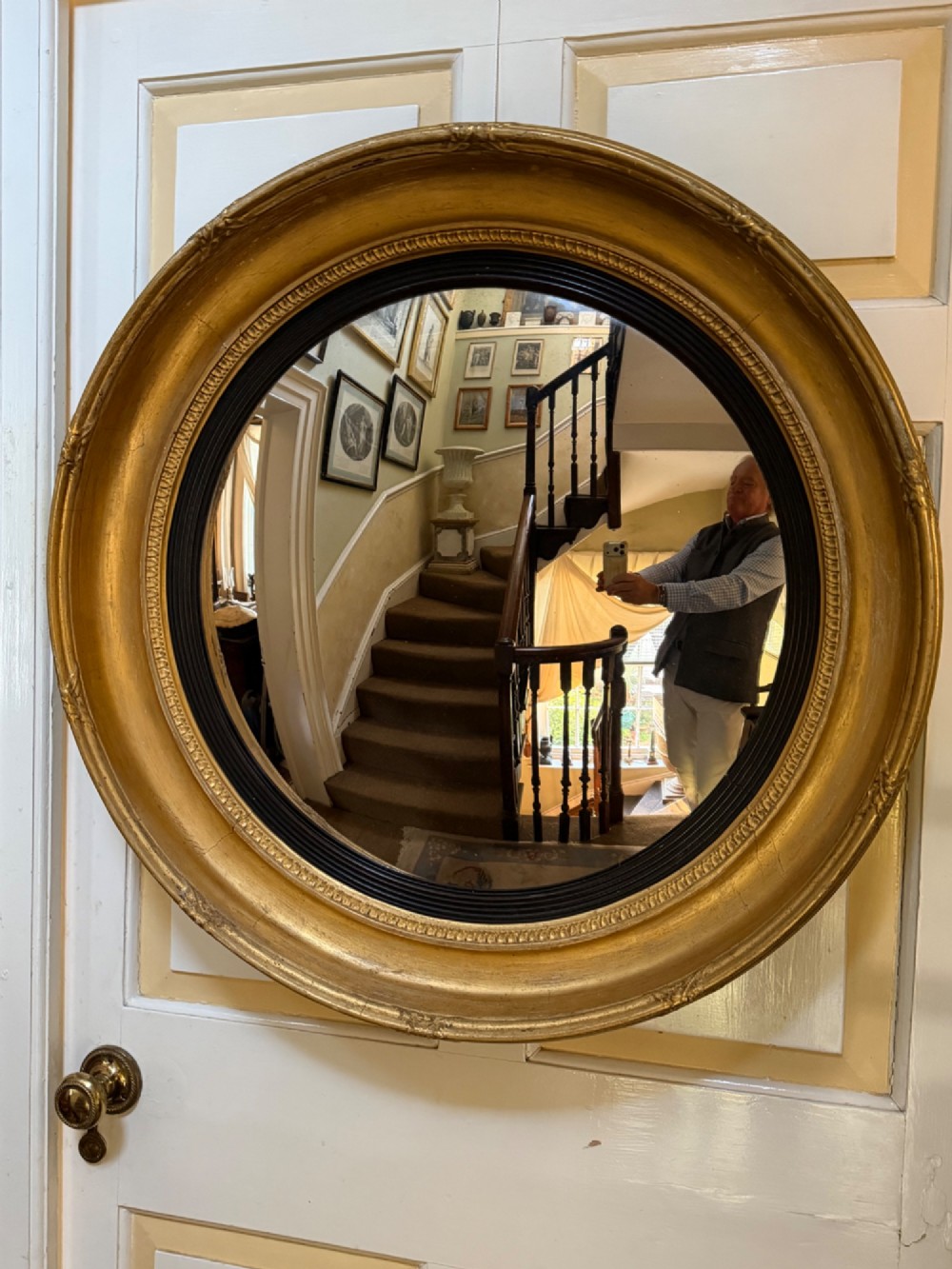 A circular early 19th-century Regency convex mirror featuring a gilded carved frame with an ebonised inner reeded slip. View XIV
