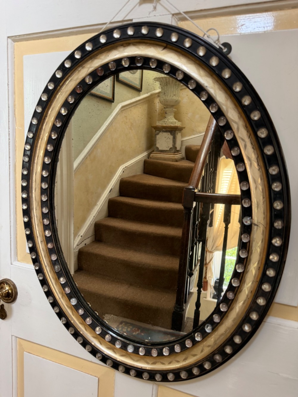 An early nineteenth-century Irish oval wall mirror featuring an ebonised and silver-gilt frame embellished with an outer border of faceted glass cabochons. View III