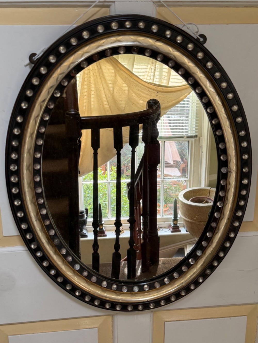 An early nineteenth-century Irish oval wall mirror featuring an ebonised and silver-gilt frame embellished with an outer border of faceted glass cabochons. View VIII