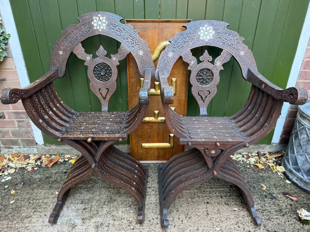 A pair of late nineteenth-century Syrian armchairs crafted from dark carved wood with mother-of-pearl inlay, Arabic script panels, and curule x-frames. View V