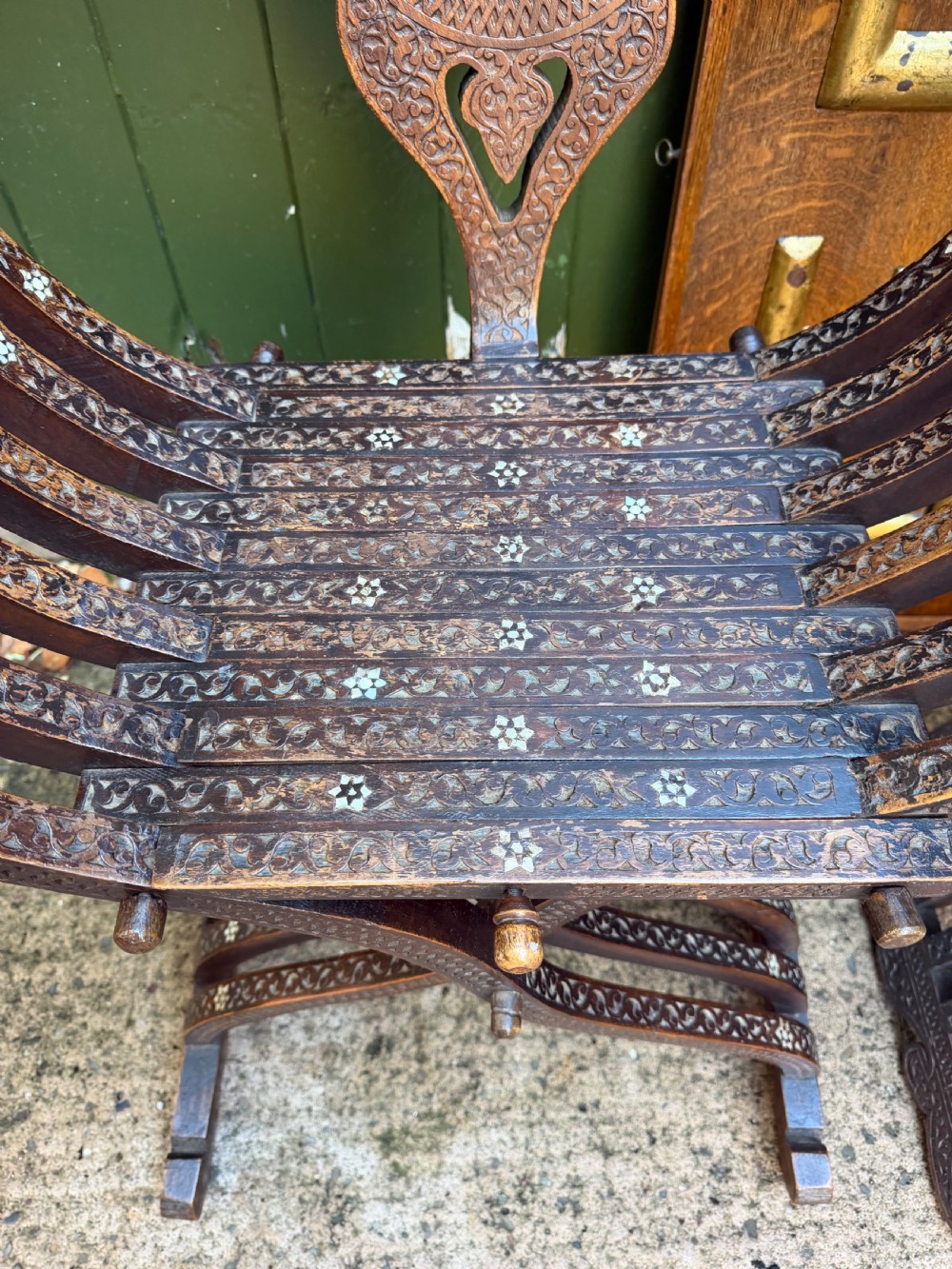 A pair of late nineteenth-century Syrian armchairs crafted from dark carved wood with mother-of-pearl inlay, Arabic script panels, and curule x-frames. View VIII