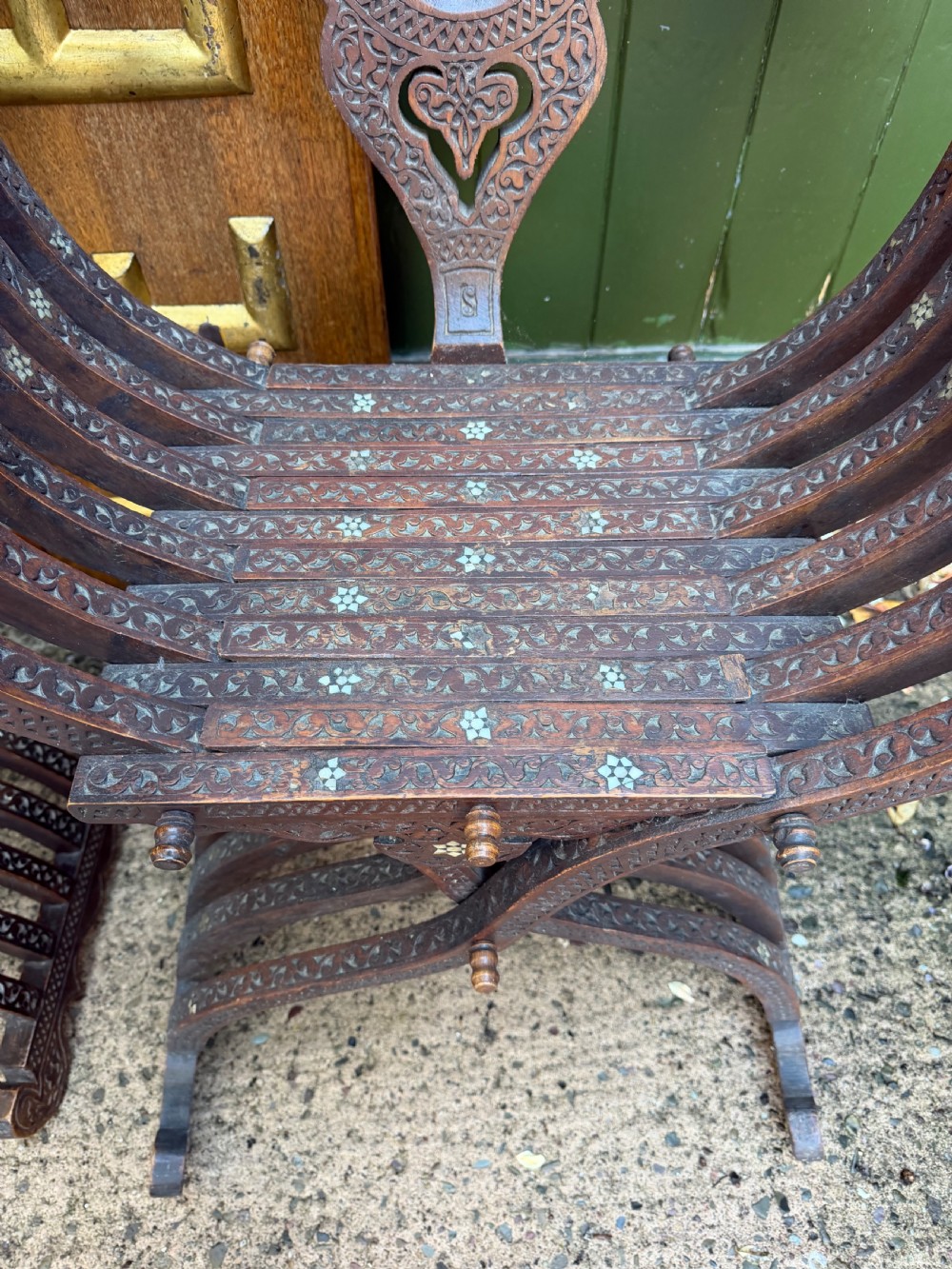 A pair of late nineteenth-century Syrian armchairs crafted from dark carved wood with mother-of-pearl inlay, Arabic script panels, and curule x-frames. View IX