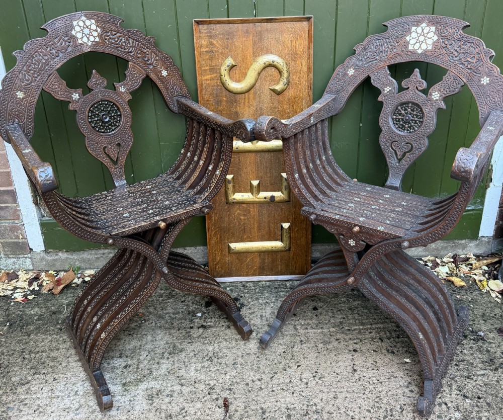 A pair of late nineteenth-century Syrian armchairs crafted from dark carved wood with mother-of-pearl inlay, Arabic script panels, and curule x-frames. View VI