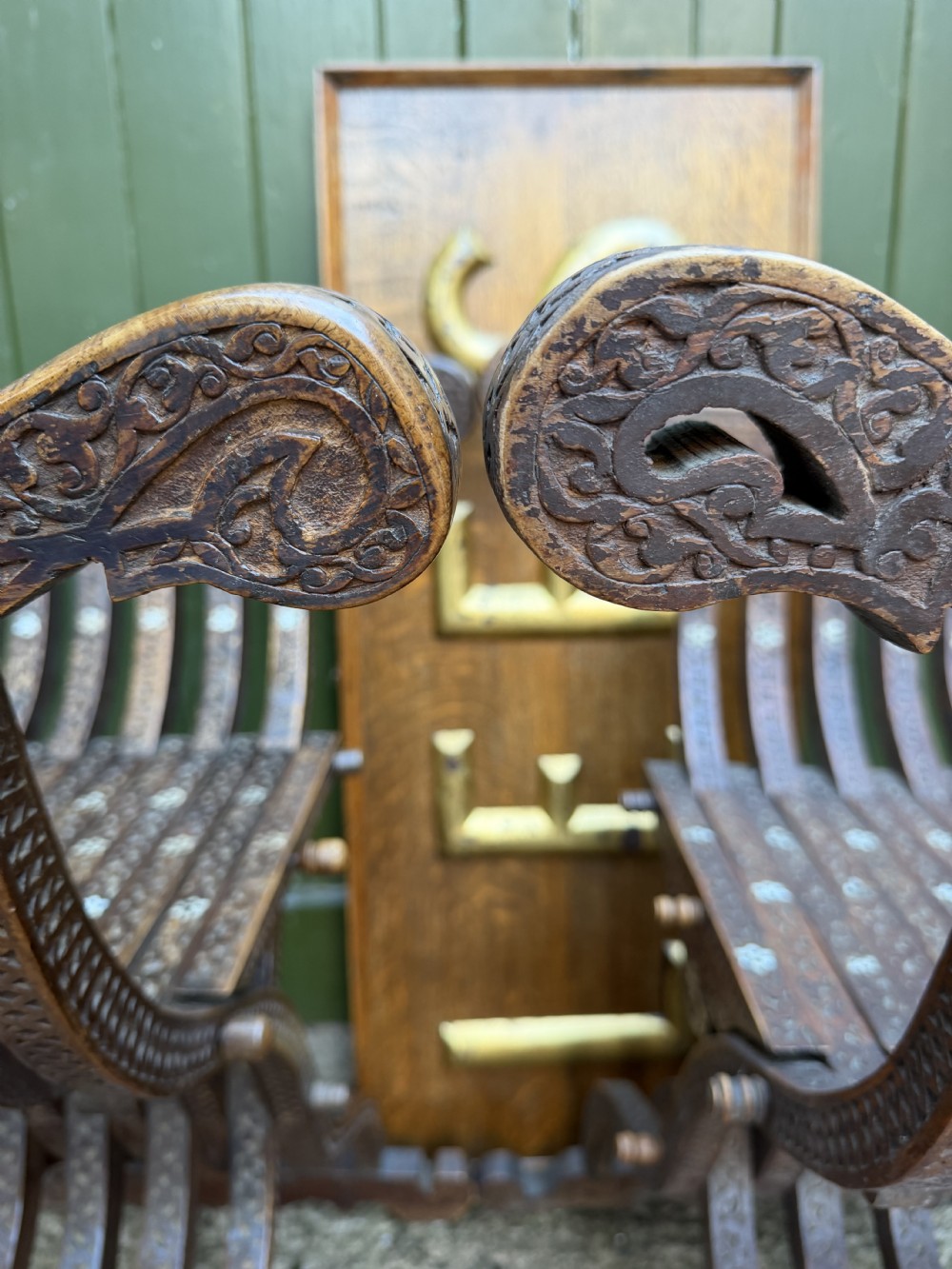A pair of late nineteenth-century Syrian armchairs crafted from dark carved wood with mother-of-pearl inlay, Arabic script panels, and curule x-frames. View XI