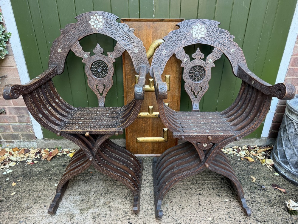 A pair of late nineteenth-century Syrian armchairs crafted from dark carved wood with mother-of-pearl inlay, Arabic script panels, and curule x-frames. View XVII