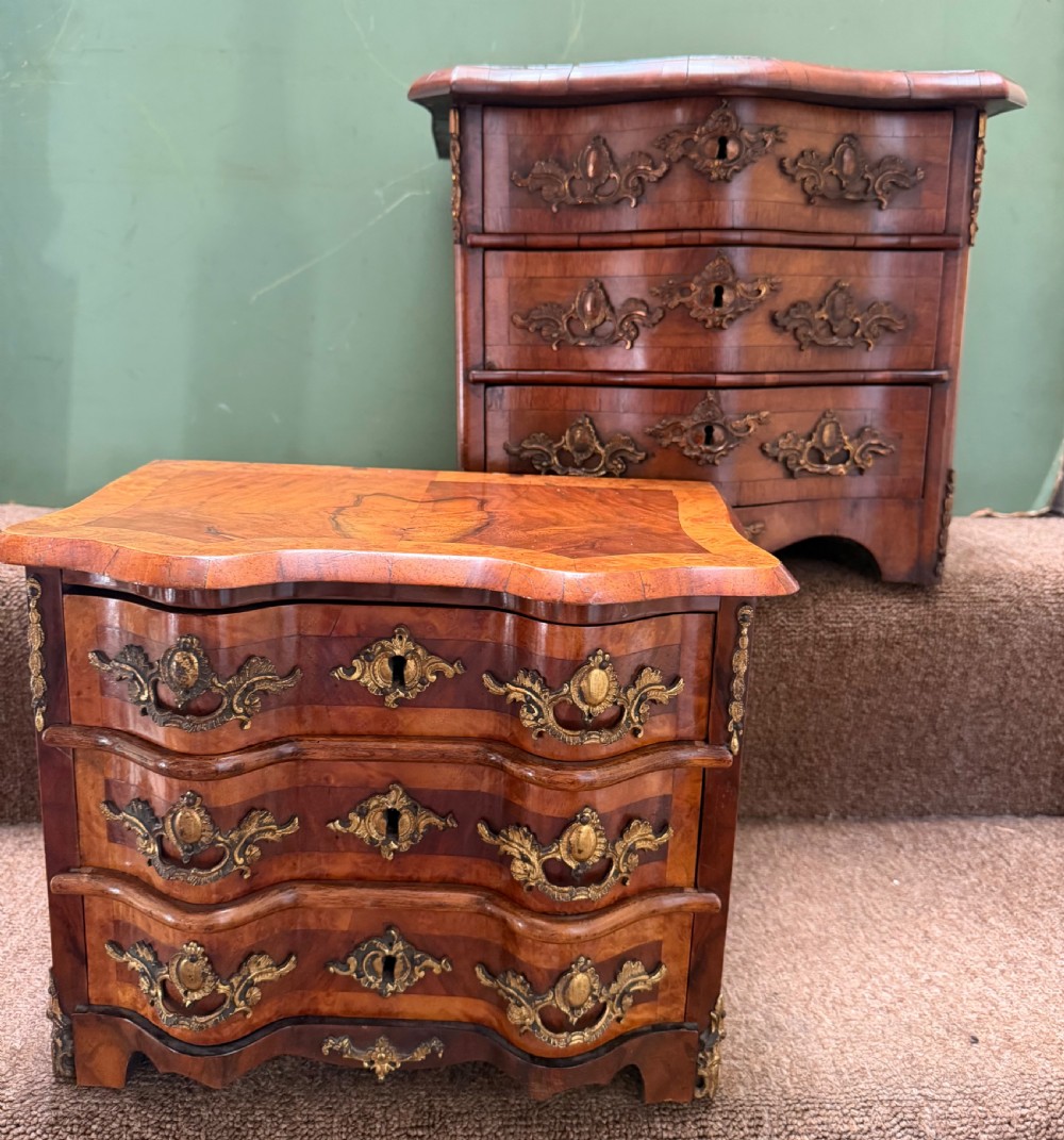 A matched pair of late nineteenth-century French miniature walnut commodes featuring serpentine three-drawer fronts and cast gilt-bronze mounts.