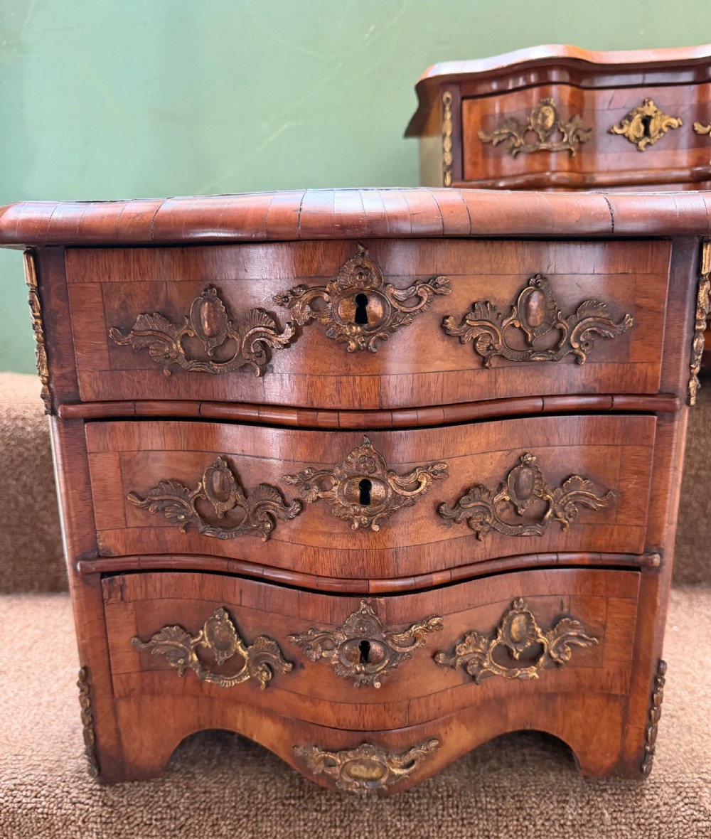 A matched pair of late nineteenth-century French miniature walnut commodes featuring serpentine three-drawer fronts and cast gilt-bronze mounts. View III