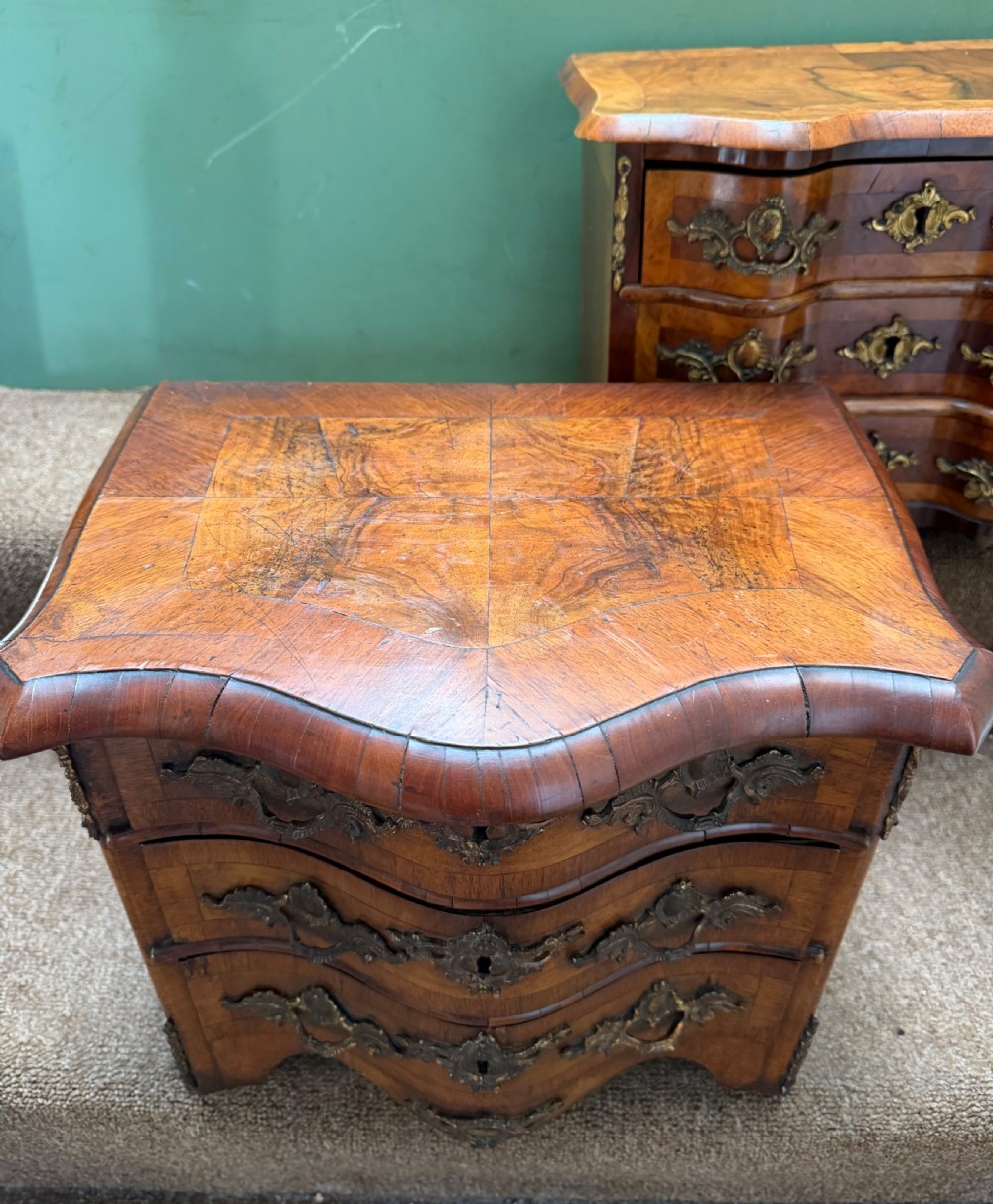 A matched pair of late nineteenth-century French miniature walnut commodes featuring serpentine three-drawer fronts and cast gilt-bronze mounts. View IV
