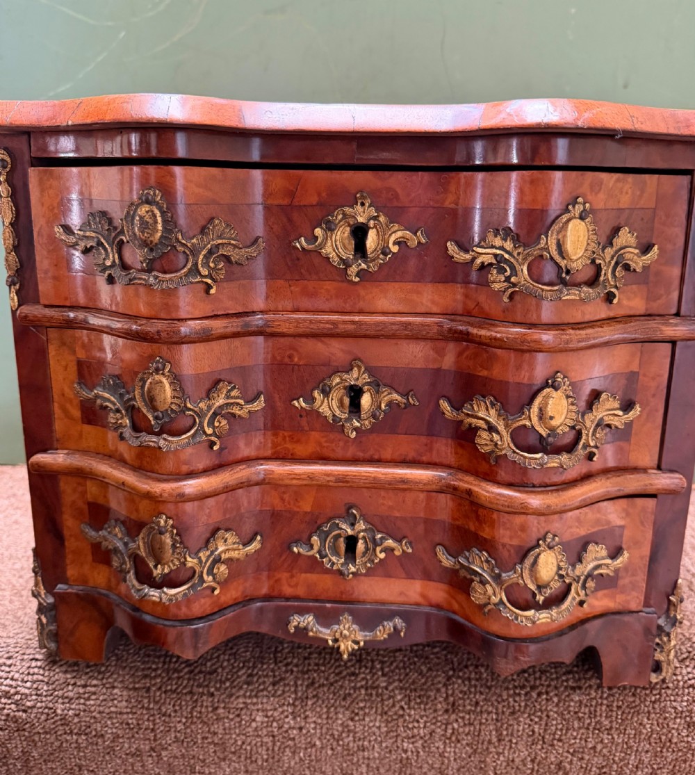 A matched pair of late nineteenth-century French miniature walnut commodes featuring serpentine three-drawer fronts and cast gilt-bronze mounts. View V