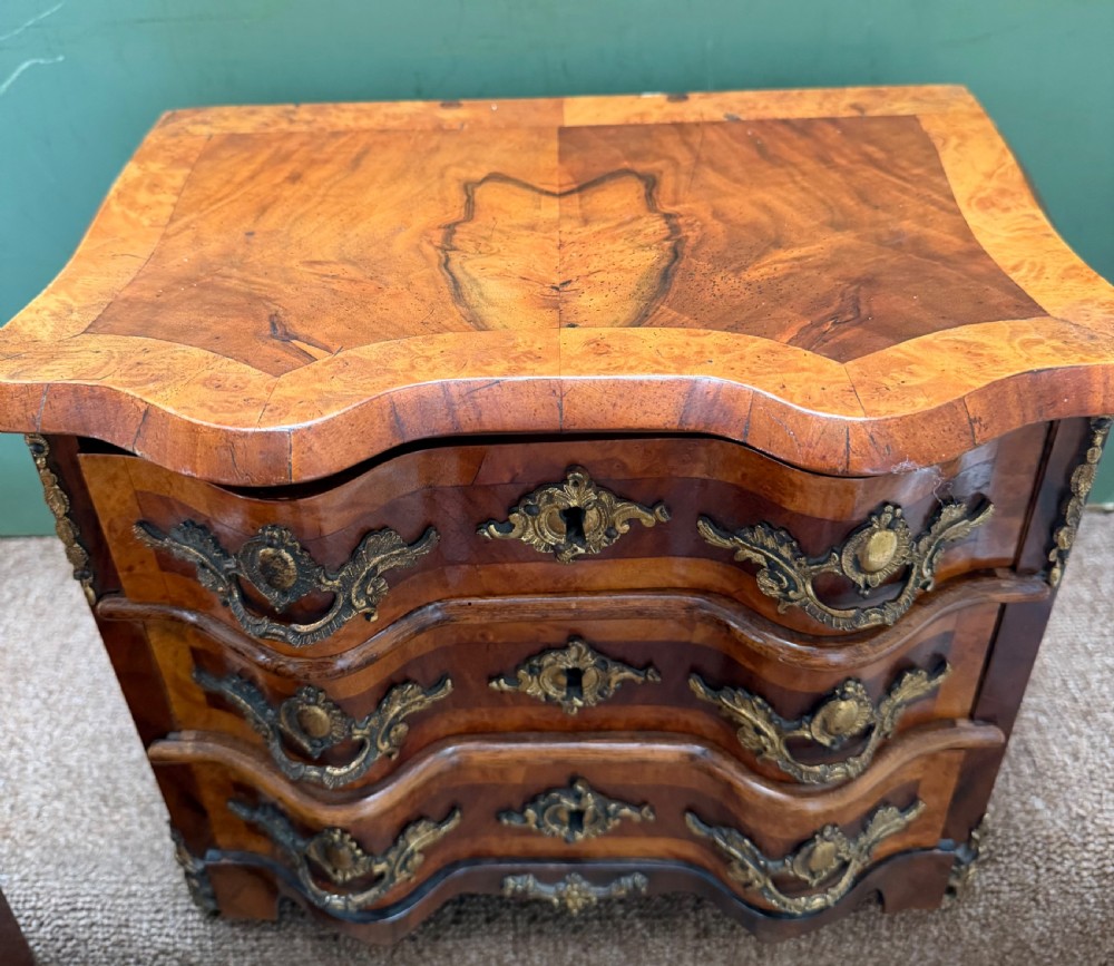 A matched pair of late nineteenth-century French miniature walnut commodes featuring serpentine three-drawer fronts and cast gilt-bronze mounts. View VI