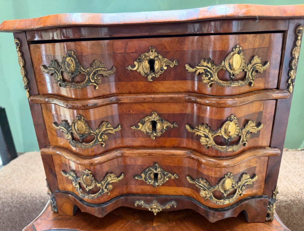A matched pair of late nineteenth-century French miniature walnut commodes featuring serpentine three-drawer fronts and cast gilt-bronze mounts. View VIII