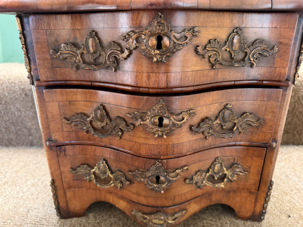 A matched pair of late nineteenth-century French miniature walnut commodes featuring serpentine three-drawer fronts and cast gilt-bronze mounts. View IX