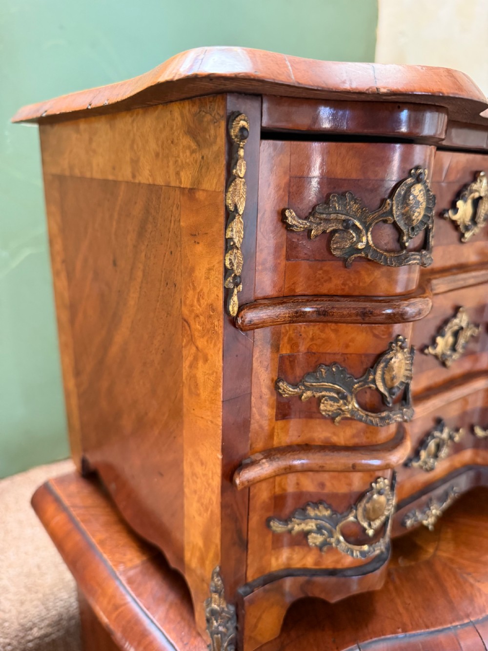 A matched pair of late nineteenth-century French miniature walnut commodes featuring serpentine three-drawer fronts and cast gilt-bronze mounts. View X