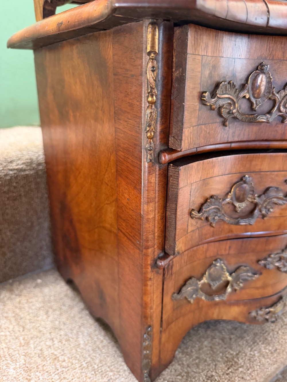 A matched pair of late nineteenth-century French miniature walnut commodes featuring serpentine three-drawer fronts and cast gilt-bronze mounts. View XI