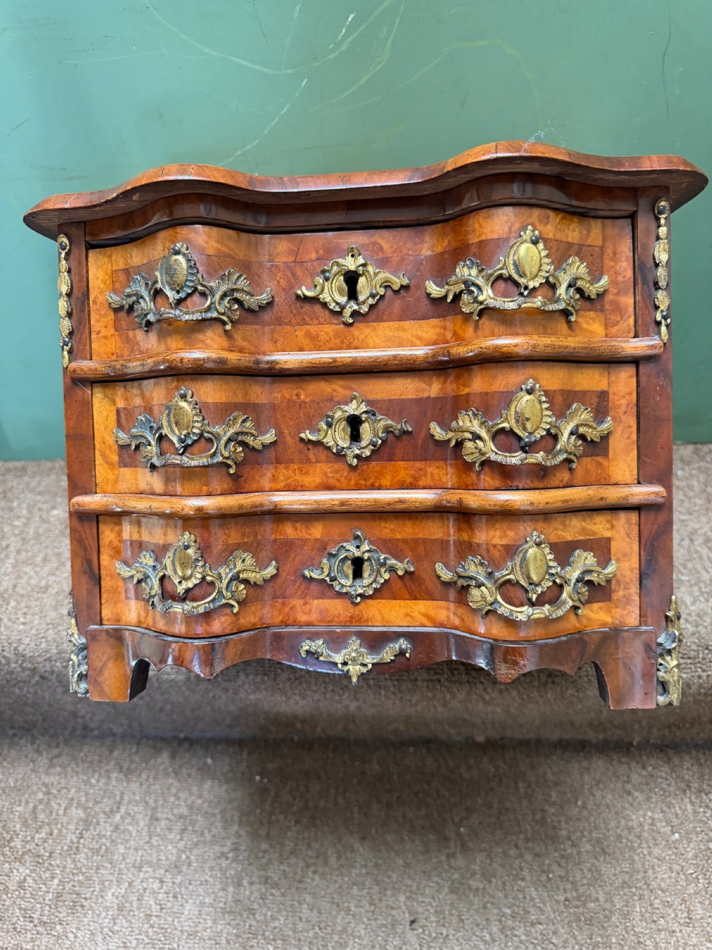 A matched pair of late nineteenth-century French miniature walnut commodes featuring serpentine three-drawer fronts and cast gilt-bronze mounts. View XII