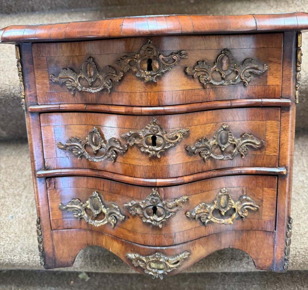 A matched pair of late nineteenth-century French miniature walnut commodes featuring serpentine three-drawer fronts and cast gilt-bronze mounts. View XIII