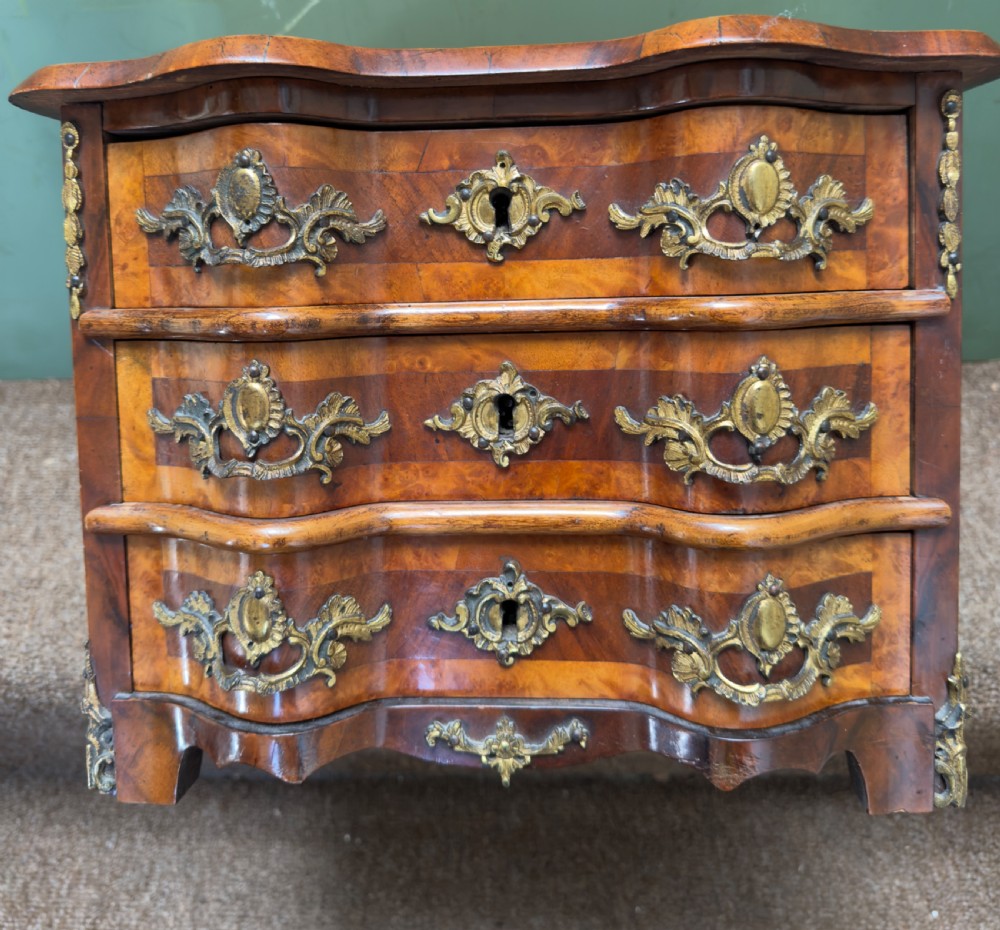 A matched pair of late nineteenth-century French miniature walnut commodes featuring serpentine three-drawer fronts and cast gilt-bronze mounts. View XIV