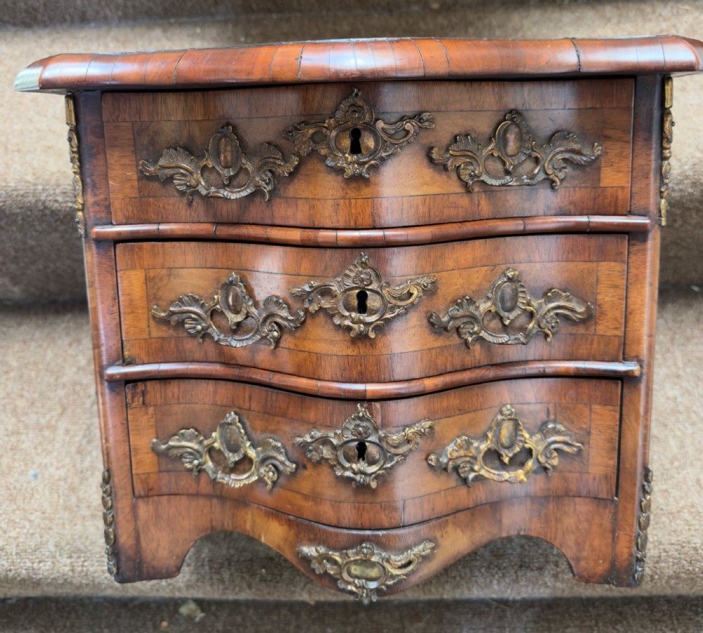 A matched pair of late nineteenth-century French miniature walnut commodes featuring serpentine three-drawer fronts and cast gilt-bronze mounts. View XV