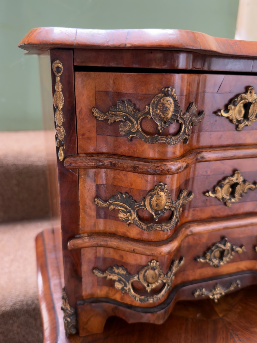 A matched pair of late nineteenth-century French miniature walnut commodes featuring serpentine three-drawer fronts and cast gilt-bronze mounts. View XVI
