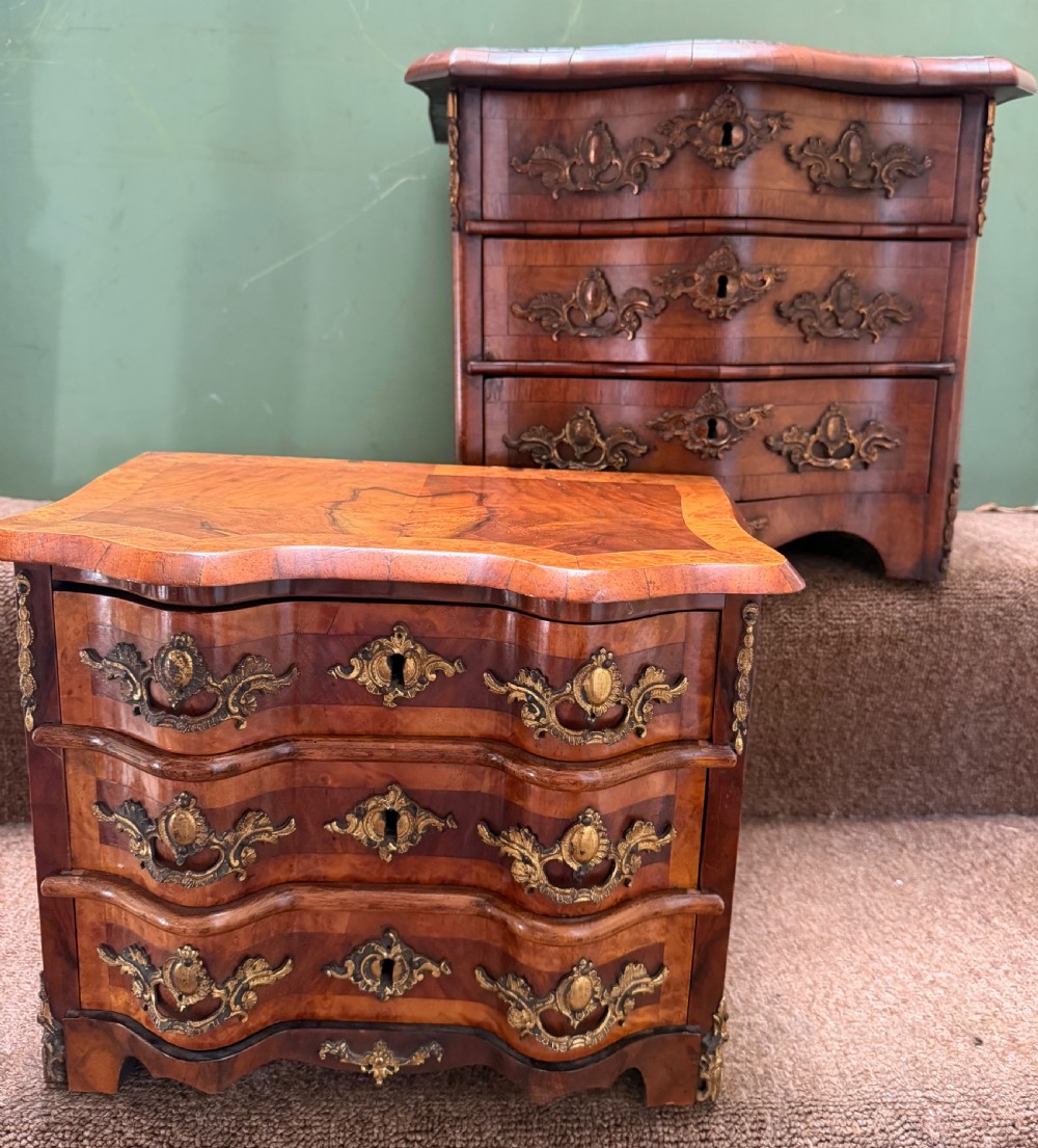 A matched pair of late nineteenth-century French miniature walnut commodes featuring serpentine three-drawer fronts and cast gilt-bronze mounts. View XVII