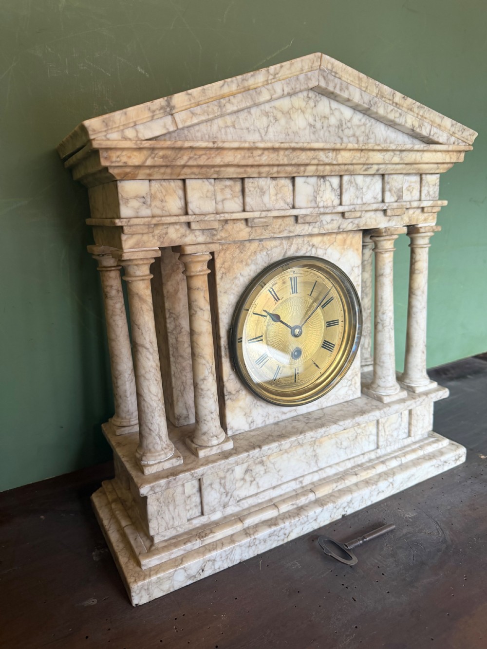 A late nineteenth-century carved cream alabaster mantel clock styled as a classical Greek temple with columns and a central brass dial. View IV