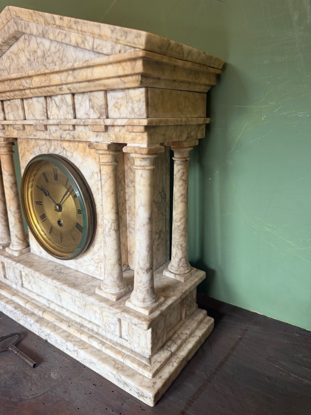 A late nineteenth-century carved cream alabaster mantel clock styled as a classical Greek temple with columns and a central brass dial. View V