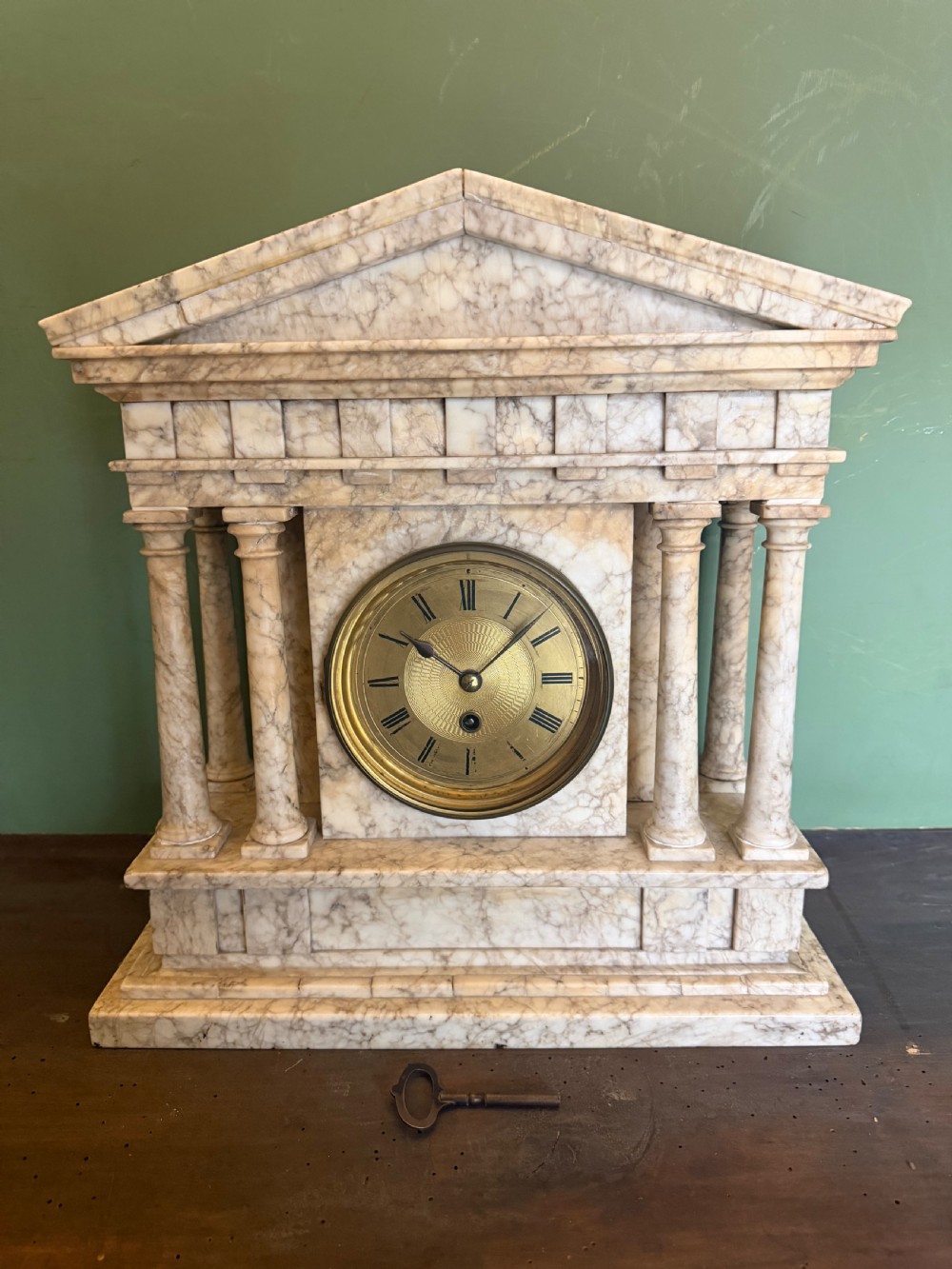 A late nineteenth-century carved cream alabaster mantel clock styled as a classical Greek temple with columns and a central brass dial. View VI