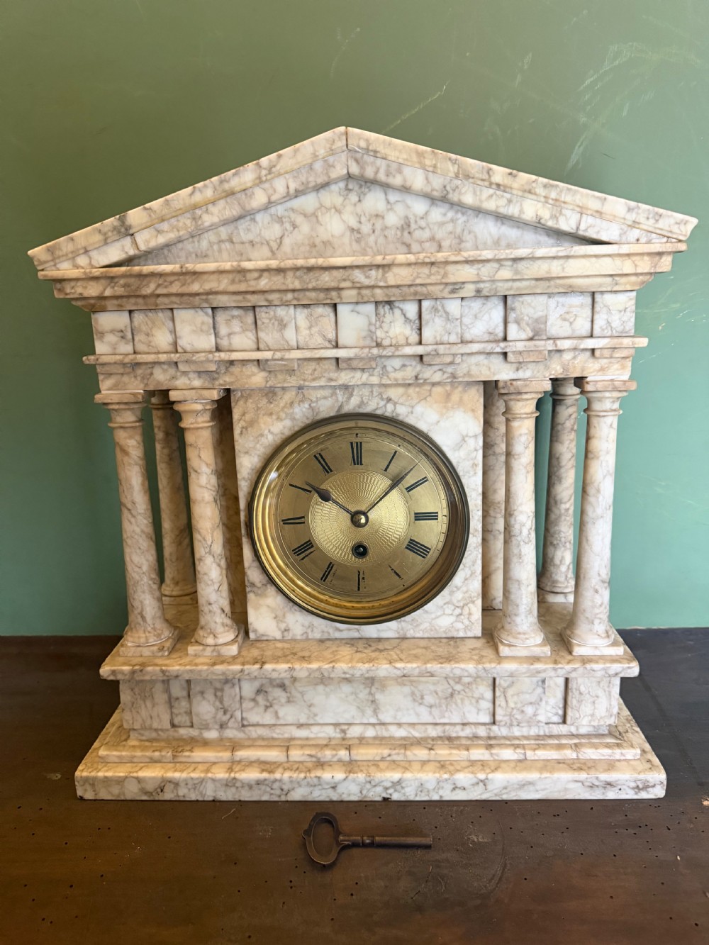 A late nineteenth-century carved cream alabaster mantel clock styled as a classical Greek temple with columns and a central brass dial. View VIII