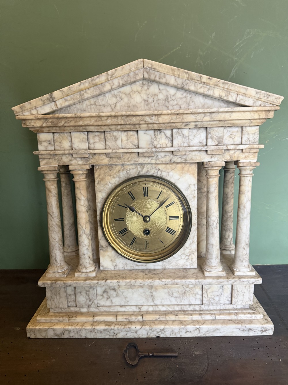 A late nineteenth-century carved cream alabaster mantel clock styled as a classical Greek temple with columns and a central brass dial. View II