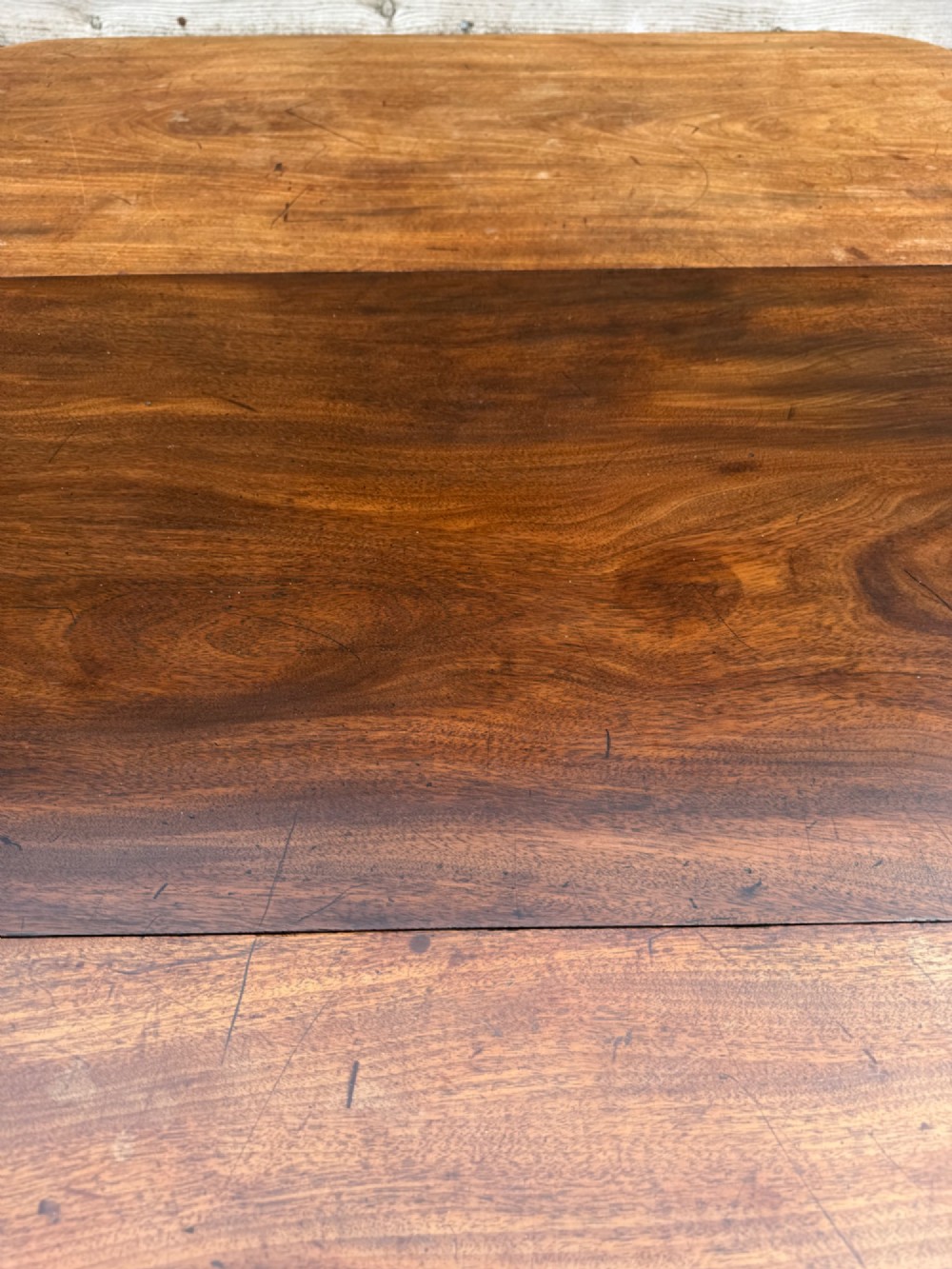 An early nineteenth-century mahogany extending dining table featuring a central reeded pedestal base with brass castors and an extra extension leaf standing behind. View VI