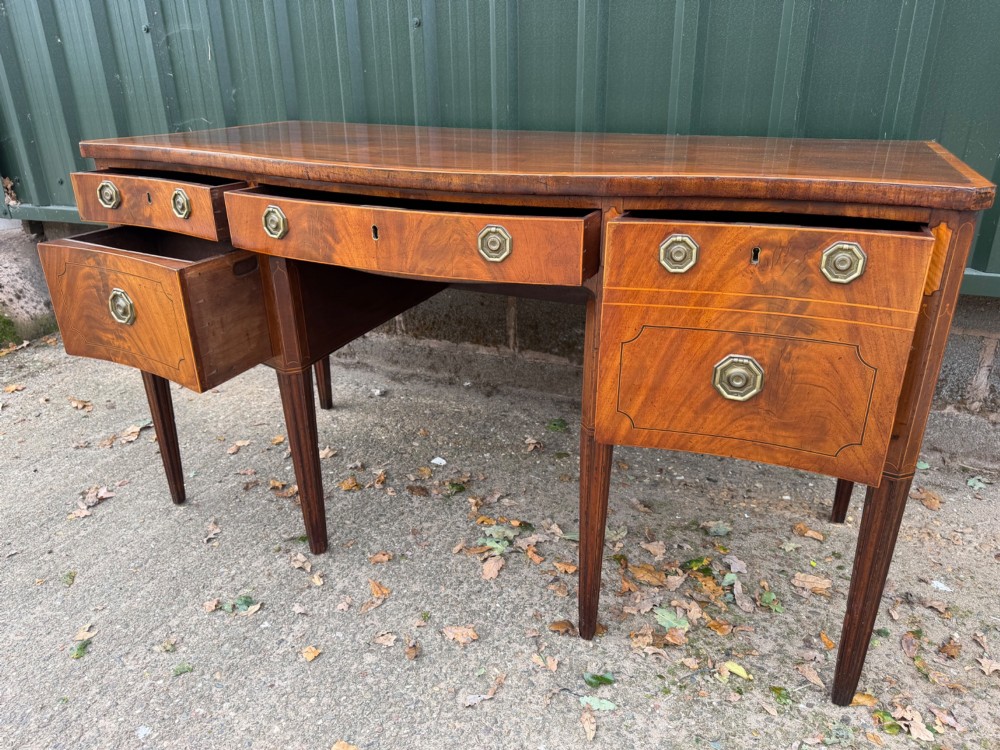 A late 18th-century George III mahogany sideboard featuring a serpentine front, stringing inlays, brass octagonal handles, and tapered square legs. View V