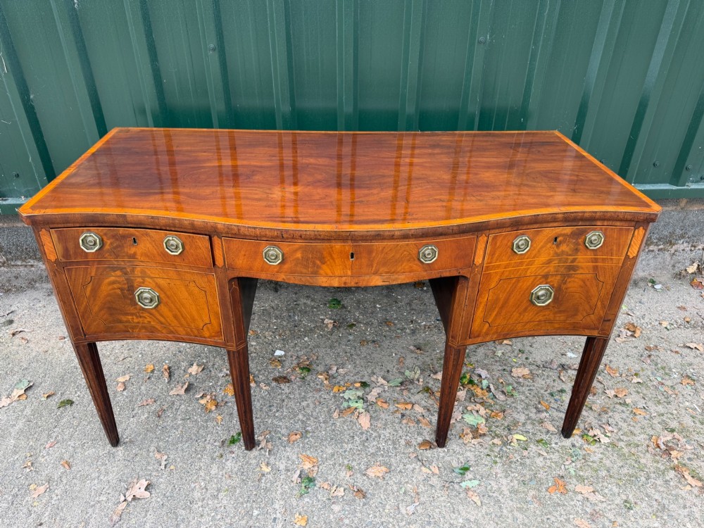 A late 18th-century George III mahogany sideboard featuring a serpentine front, stringing inlays, brass octagonal handles, and tapered square legs. View VIII