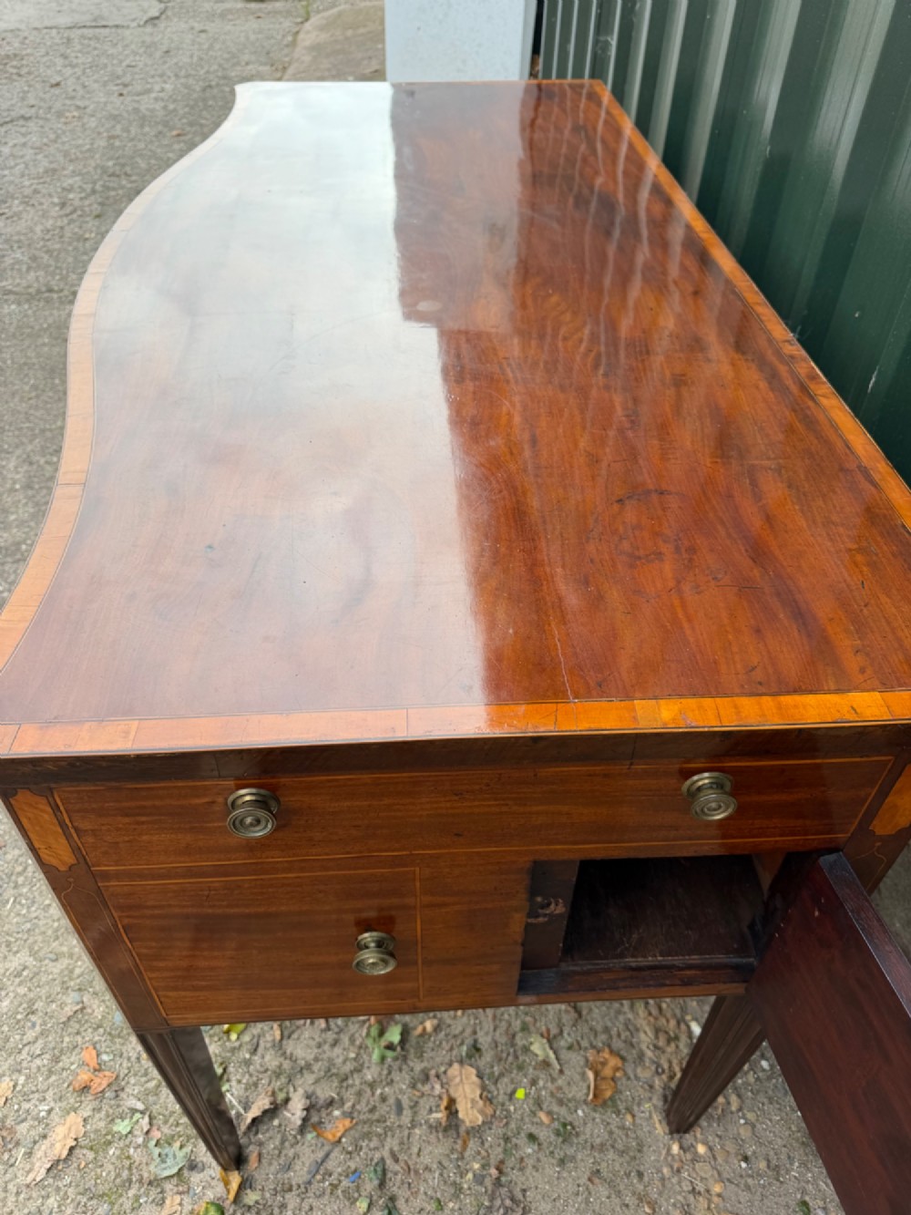 A late 18th-century George III mahogany sideboard featuring a serpentine front, stringing inlays, brass octagonal handles, and tapered square legs. View X