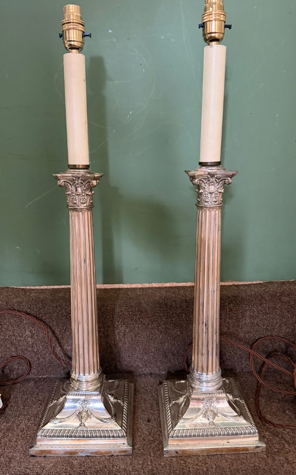 A pair of late nineteenth-century silver-plated table lamps designed as fluted Corinthian columns on square stepped bases with classical swag relief. View II