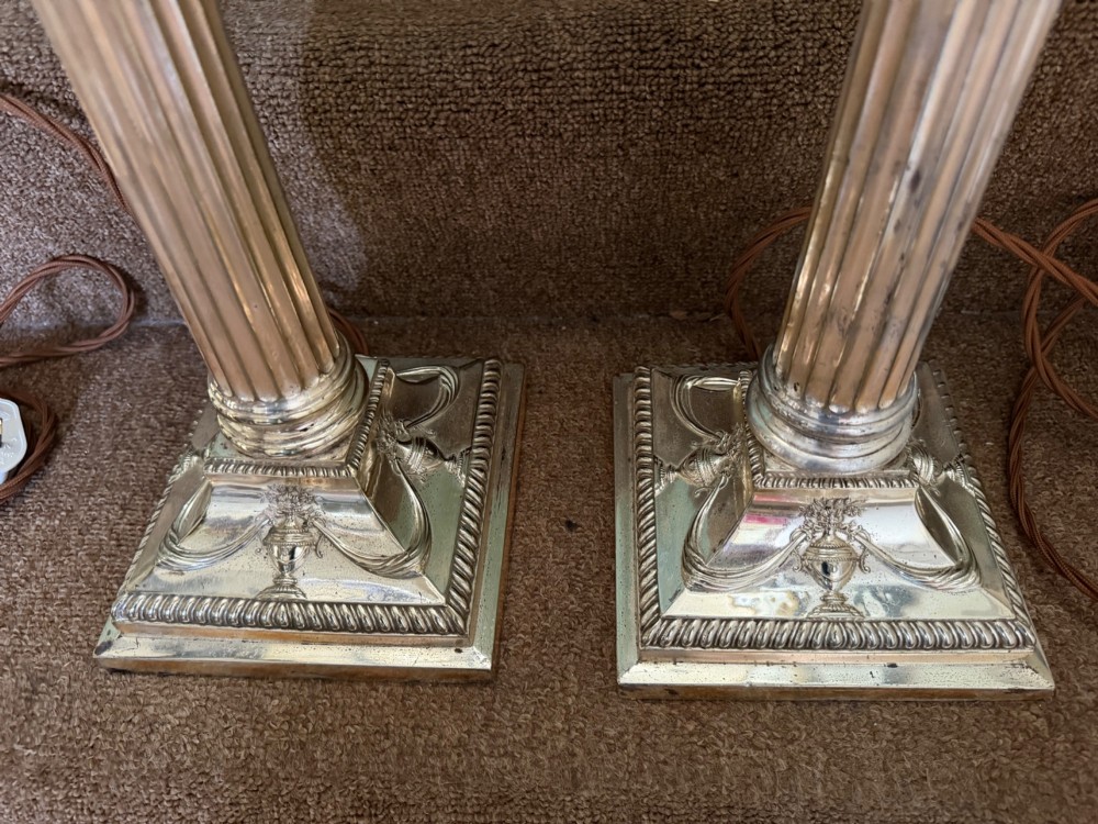 A pair of late nineteenth-century silver-plated table lamps designed as fluted Corinthian columns on square stepped bases with classical swag relief. View VI