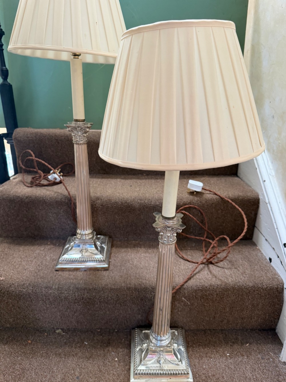 A pair of late nineteenth-century silver-plated table lamps designed as fluted Corinthian columns on square stepped bases with classical swag relief. View XII