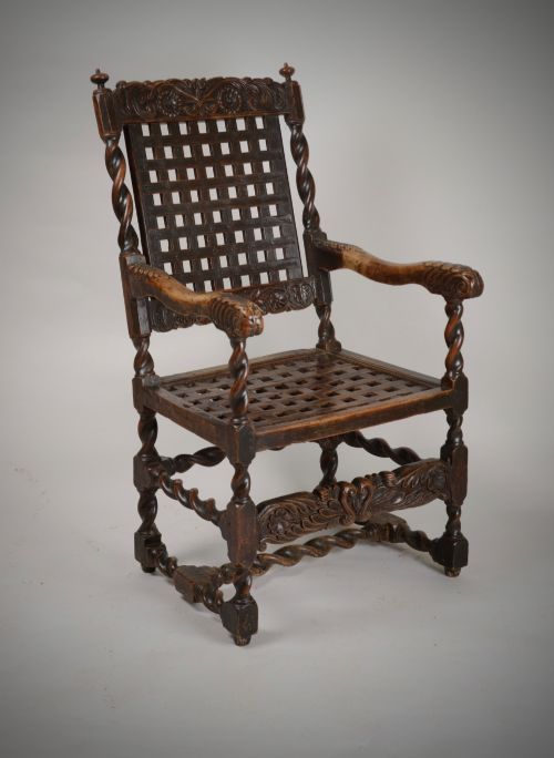 fig 1. A dark walnut Charles II style open armchair featuring intricate barley twist uprights, a carved floral cresting rail, a slatted timber lattice back, and turned stretchers.