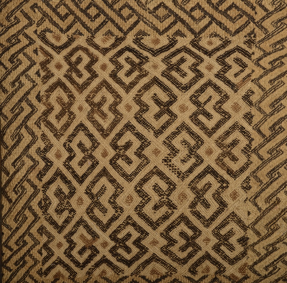 An early 20th-century framed Kuba cloth featuring geometric embroidered patterns woven from natural raffia fibres in shades of beige and dark brown. View II