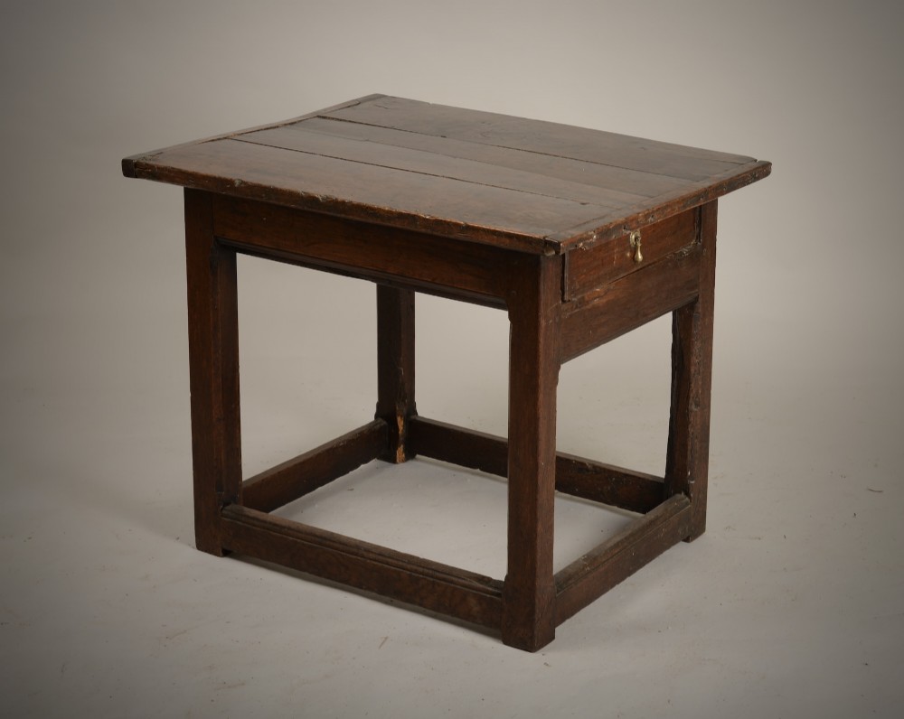 An antique dark oak low table featuring a plank top, a small side drawer with a brass drop handle, and sturdy legs joined by rectangular stretchers.