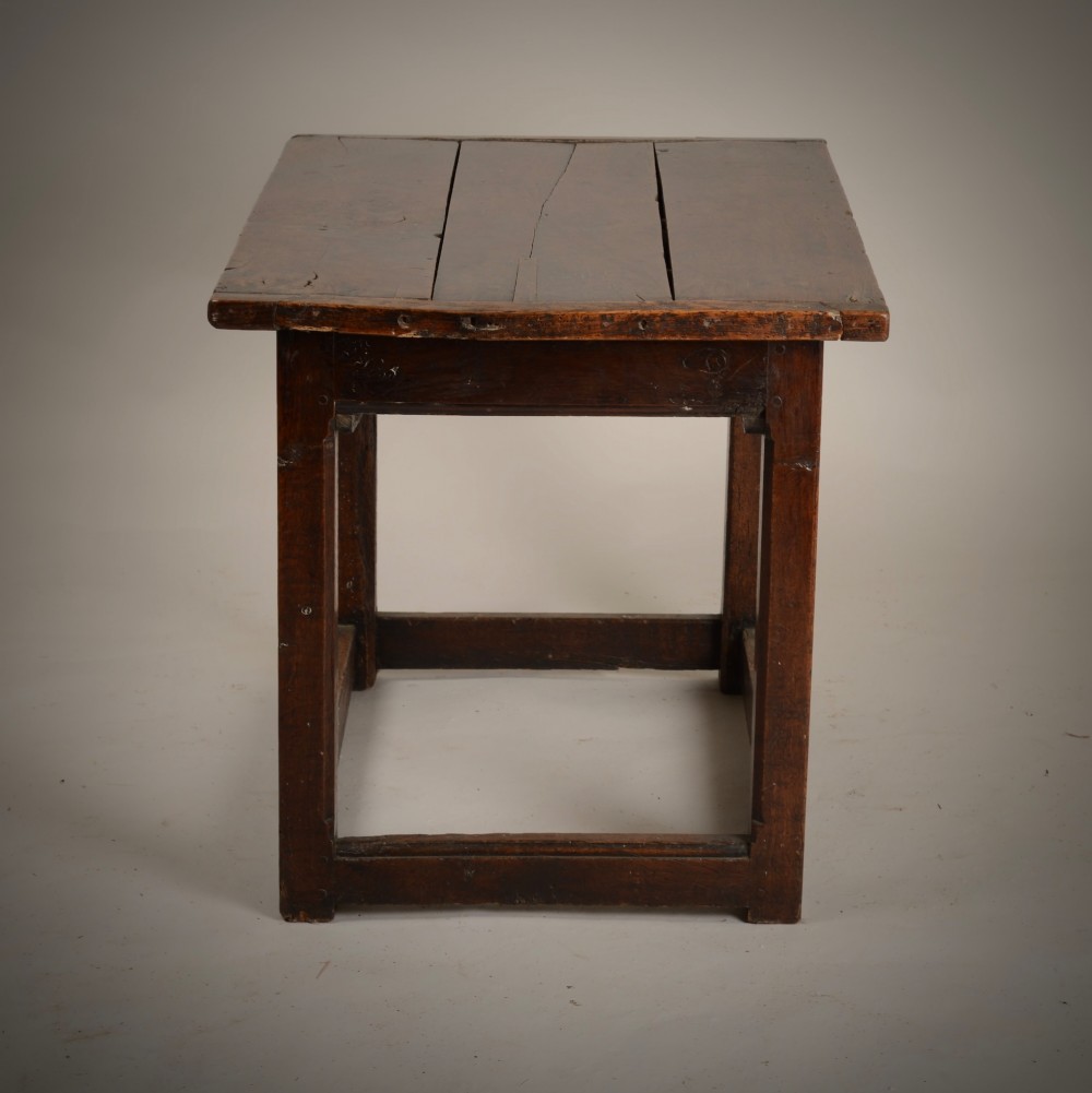 An antique dark oak low table featuring a plank top, a small side drawer with a brass drop handle, and sturdy legs joined by rectangular stretchers. View VI