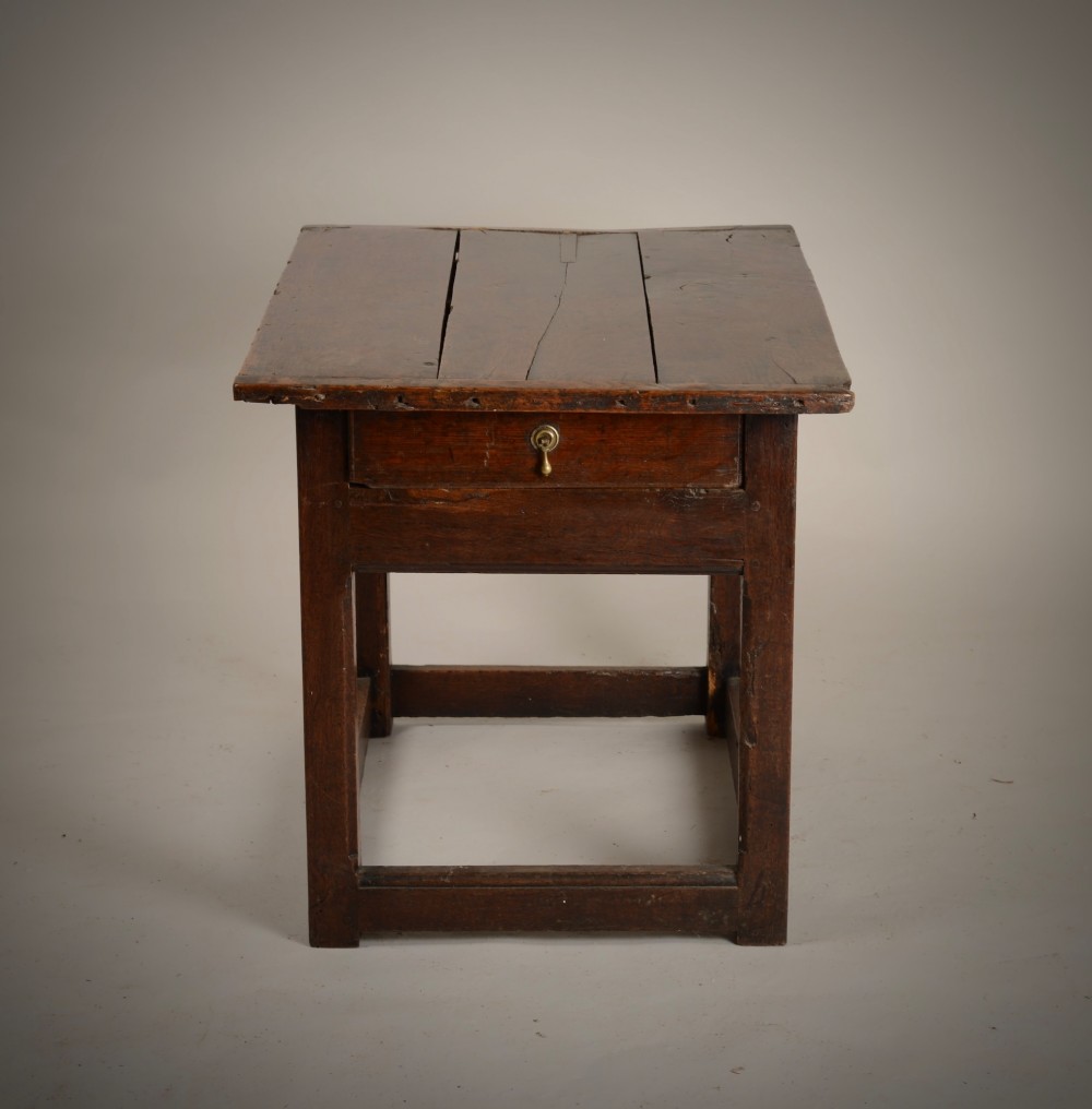 An antique dark oak low table featuring a plank top, a small side drawer with a brass drop handle, and sturdy legs joined by rectangular stretchers. View VIII